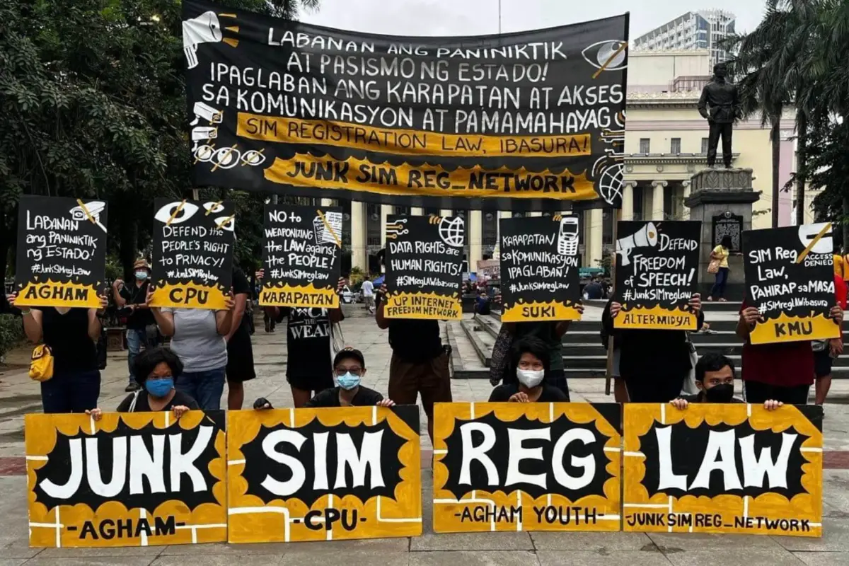 Protesters at Liwasang Bonifacio holding signs reading Junk SIM Reg Law and a banner against state surveillance
