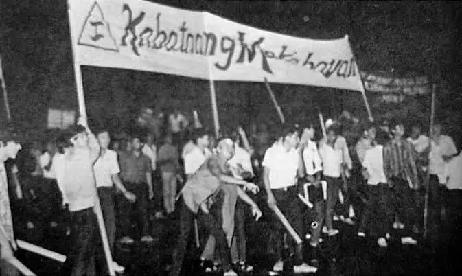Black and white photo of Kabataang Makabayan members marching under a KM banner at night